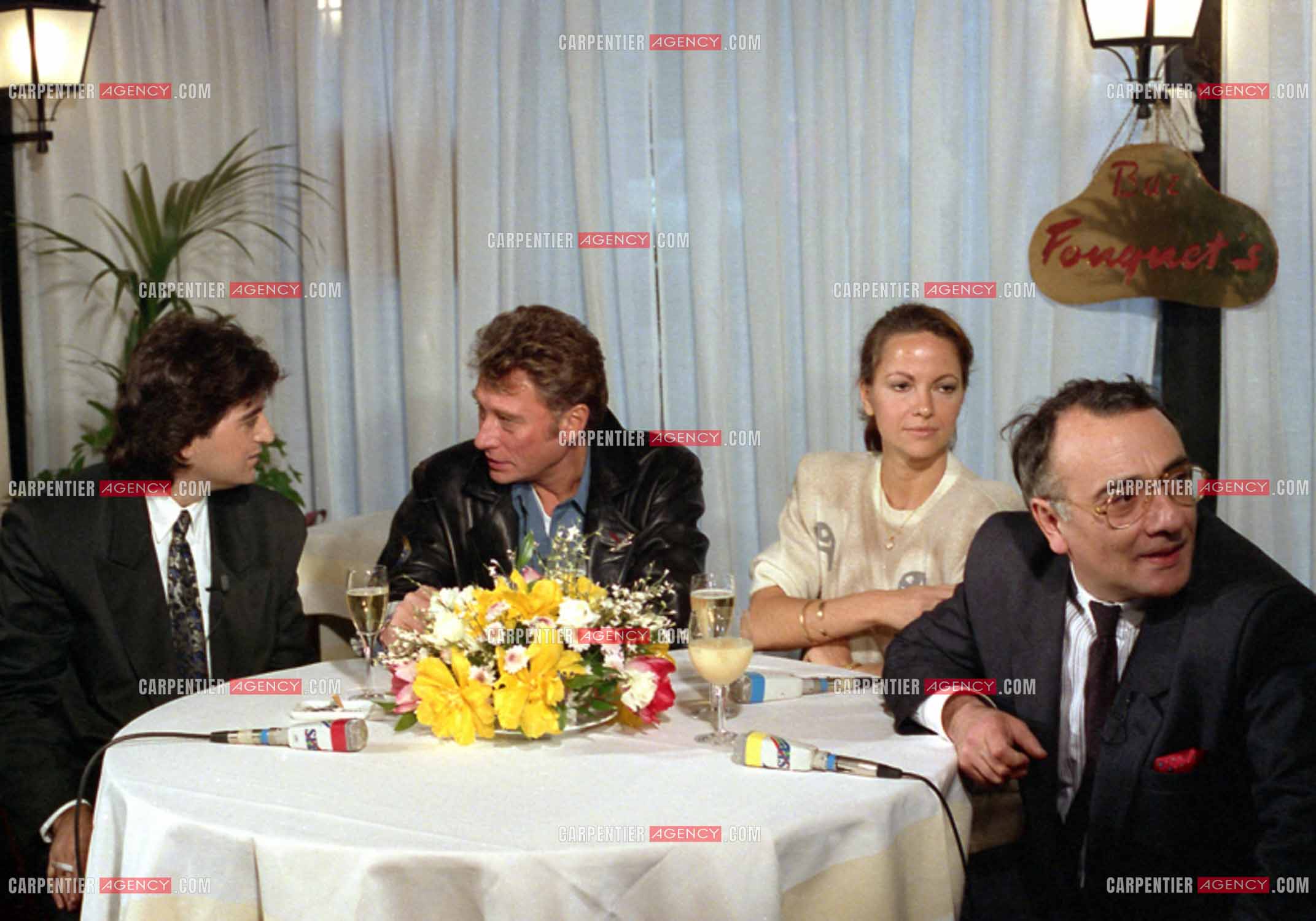 Johnny Hallyday lors du lancement de sa marque de blousons en compagnie son styliste Dany Boyadjian, de sa nouvelle compagne Gisèle Galante et Yves Mourousi à Paris le 4 février 1988.  ( Exclusif )