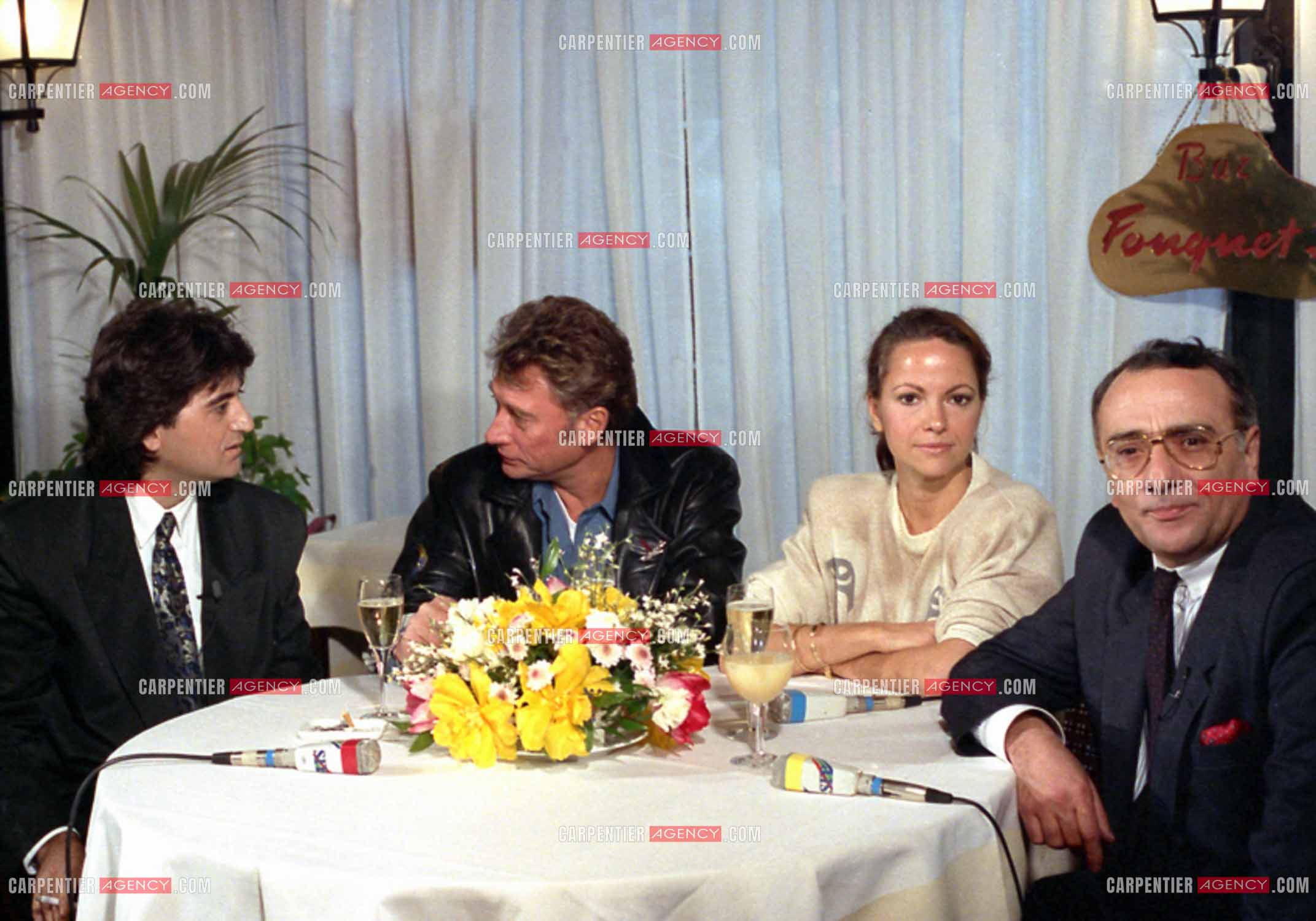 Johnny Hallyday lors du lancement de sa marque de blousons en compagnie son styliste Dany Boyadjian, de sa nouvelle compagne Gisèle Galante et Yves Mourousi à Paris le 4 février 1988.  ( Exclusif )