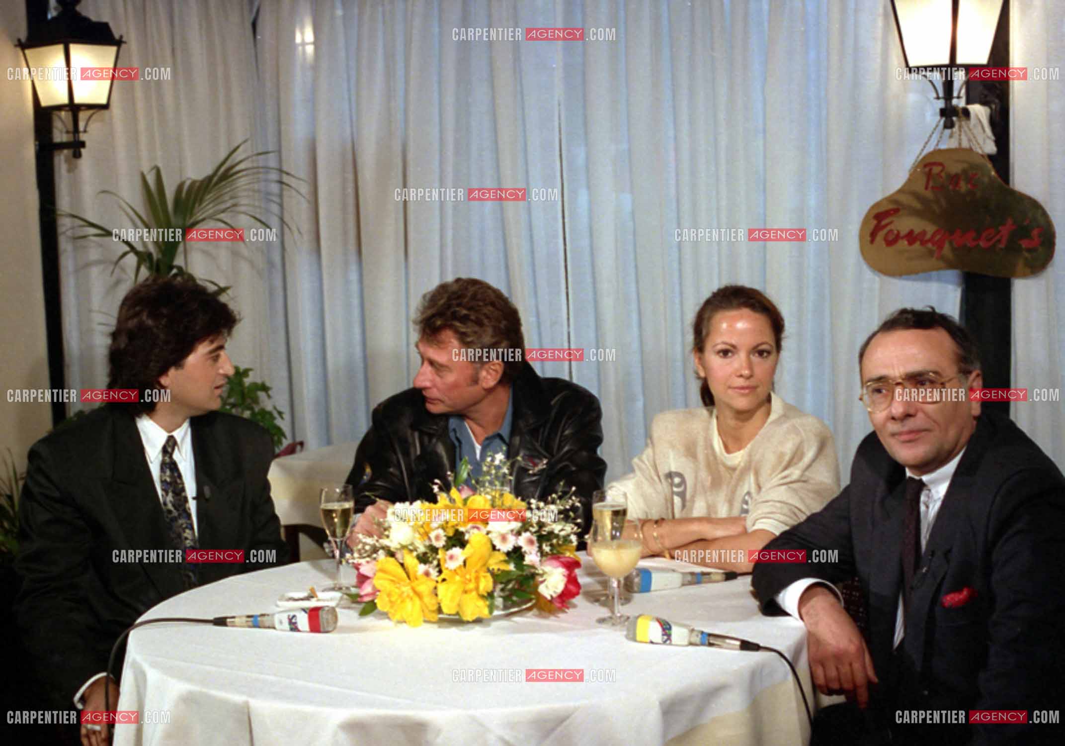 Johnny Hallyday lors du lancement de sa marque de blousons en compagnie son styliste Dany Boyadjian, de sa nouvelle compagne Gisèle Galante et Yves Mourousi à Paris le 4 février 1988.  ( Exclusif )