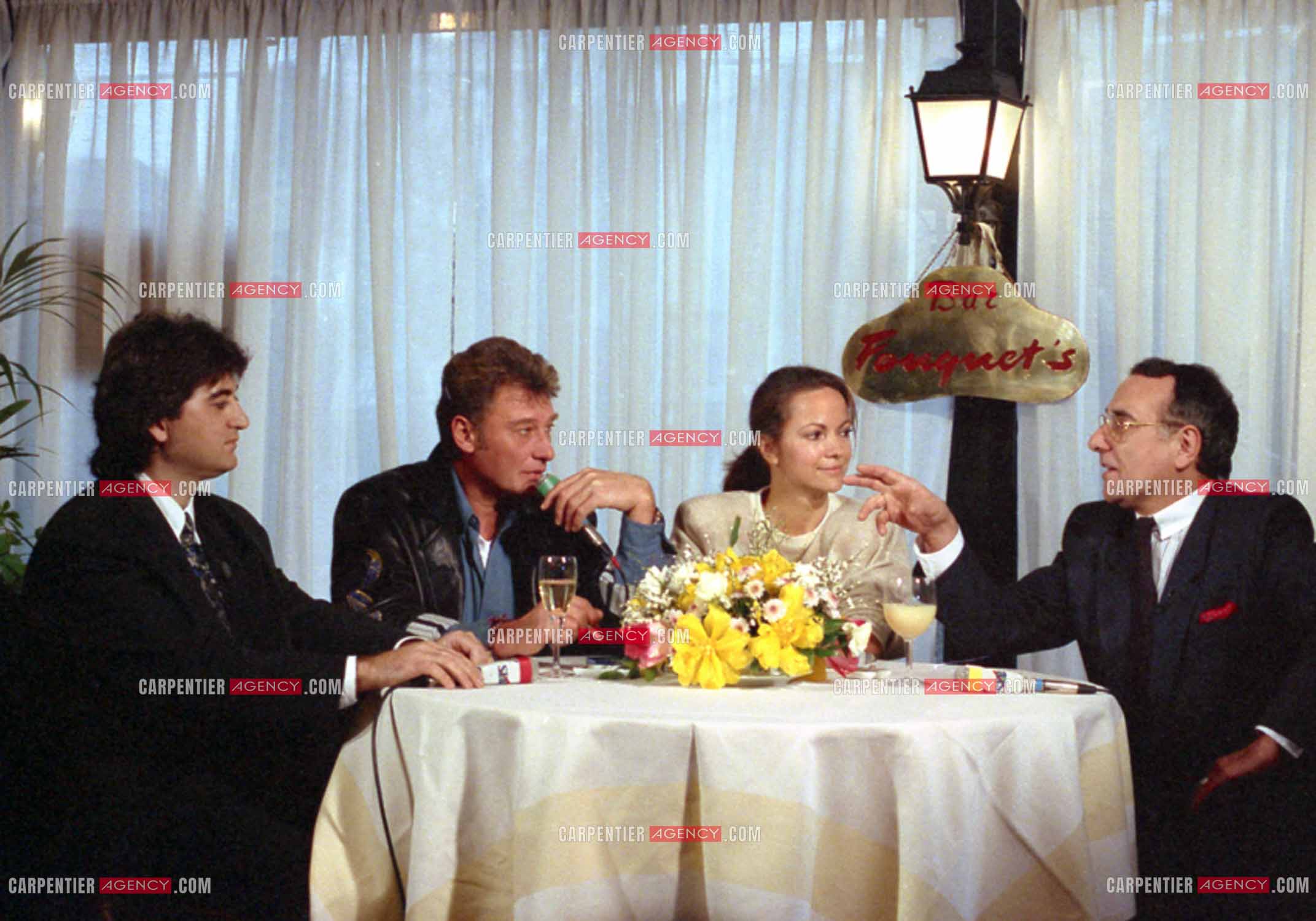 Johnny Hallyday lors du lancement de sa marque de blousons en compagnie son styliste Dany Boyadjian, de sa nouvelle compagne Gisèle Galante et Yves Mourousi à Paris le 4 février 1988.  ( Exclusif )