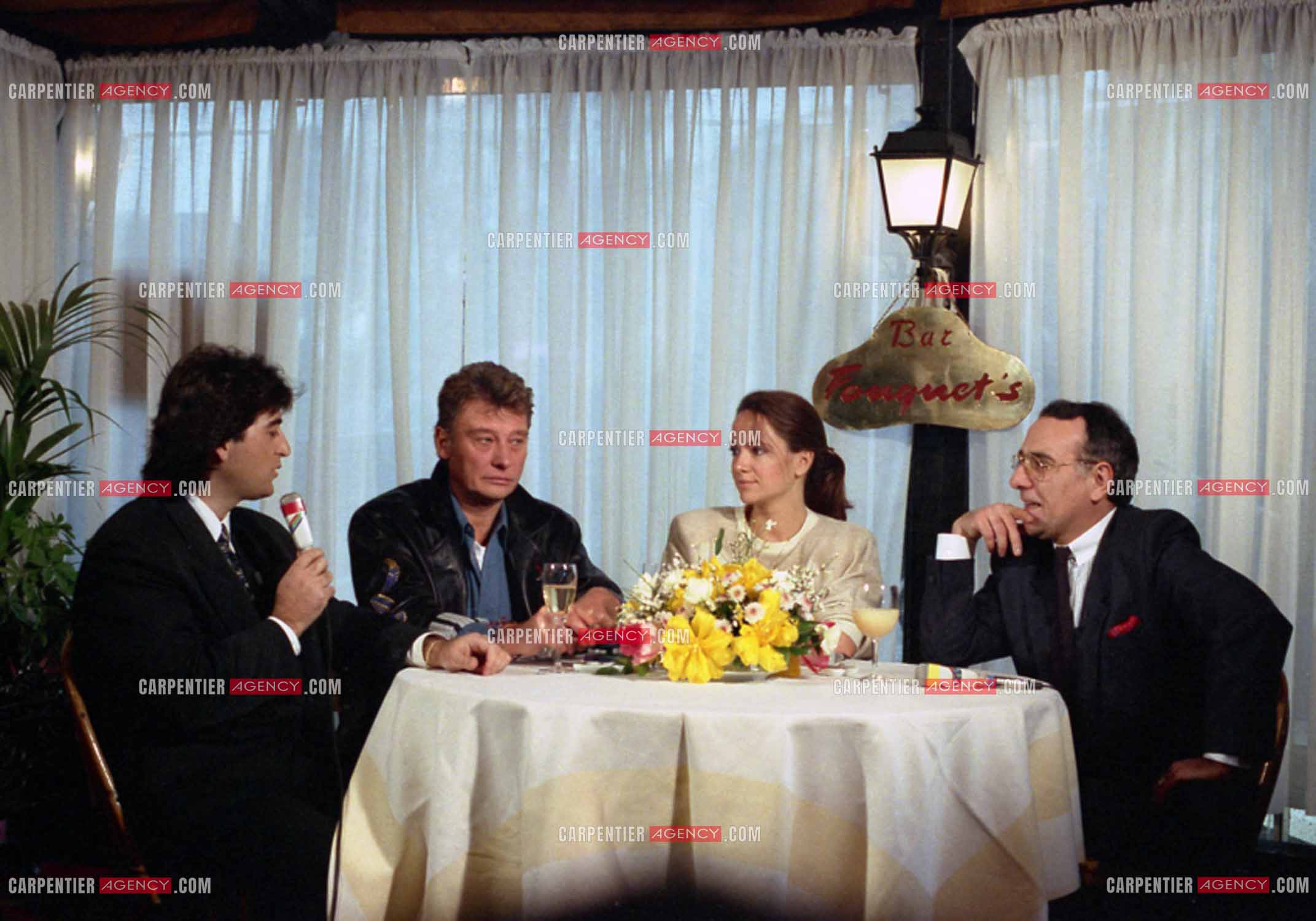 Johnny Hallyday lors du lancement de sa marque de blousons en compagnie son styliste Dany Boyadjian, de sa nouvelle compagne Gisèle Galante et Yves Mourousi à Paris le 4 février 1988.  ( Exclusif )