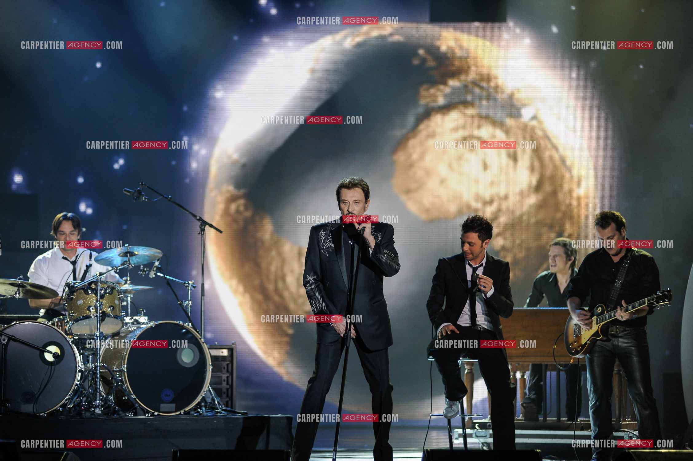 Johnny Hallyday interprète “Ça peut changer le monde“ accompagné de son fils David Hallyday à la batterie, Christophe Maé à l'armonica, et Axel Bauer à la guitare aux Victoires de la musique en 2009 au Zénith de Paris.