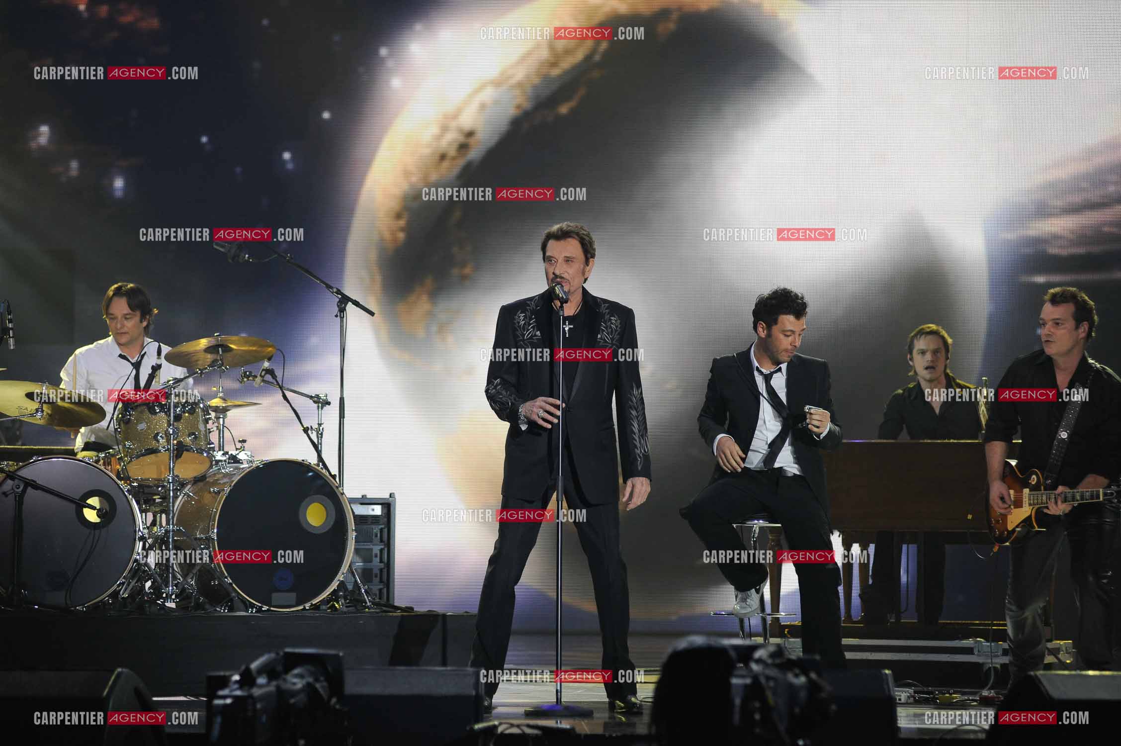 Johnny Hallyday interprète “Ça peut changer le monde“ accompagné de son fils David Hallyday à la batterie, Christophe Maé à l'armonica, et Axel Bauer à la guitare aux Victoires de la musique en 2009 au Zénith de Paris.