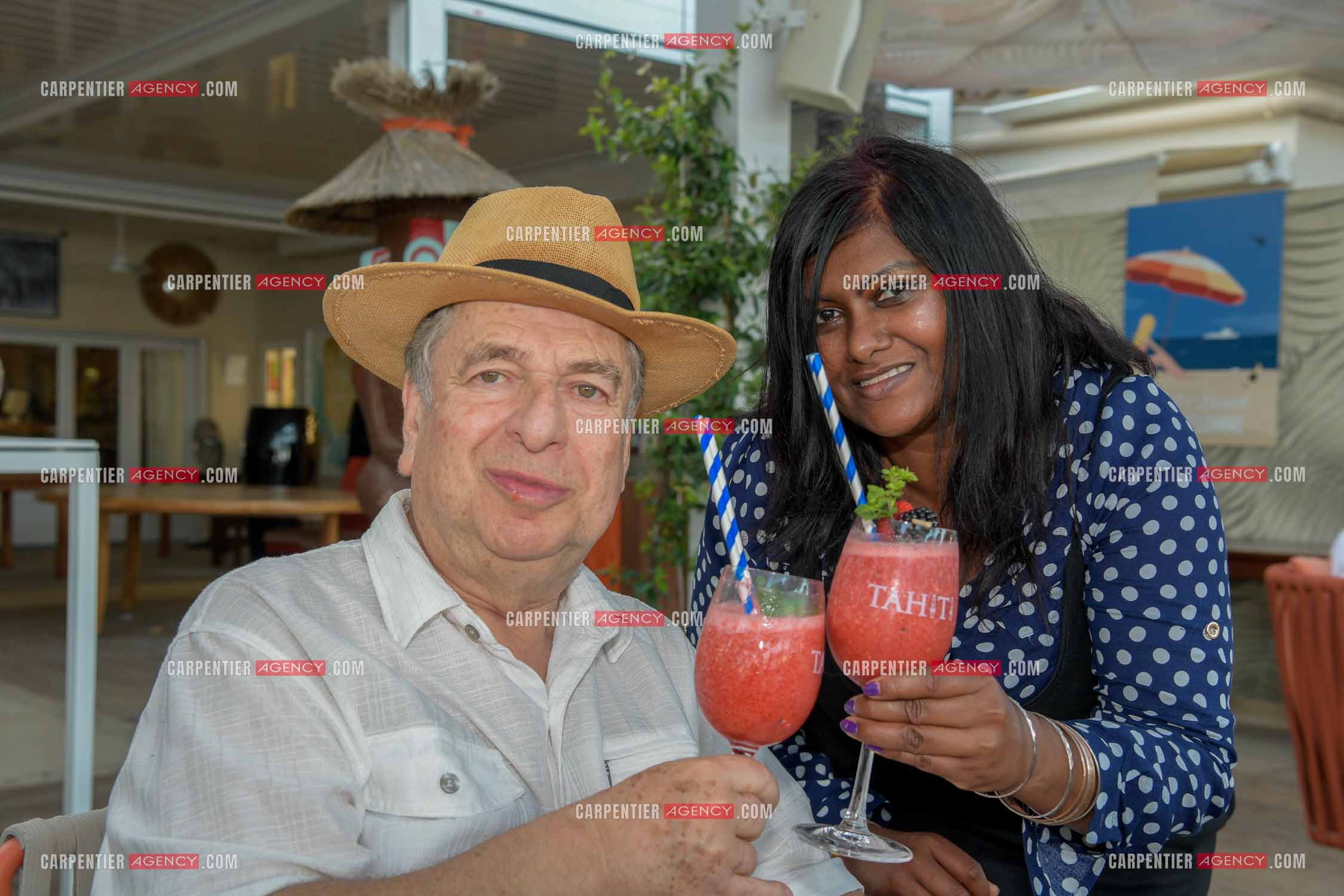 Paul-Loup Sulitzer lors d'une ballade sur le port de St Tropez. Ici en terrasse du bar de plage le " TAHAITI “  avec sa compagne  Supriya Answya Devi Rathoar.  ( Exclusif )