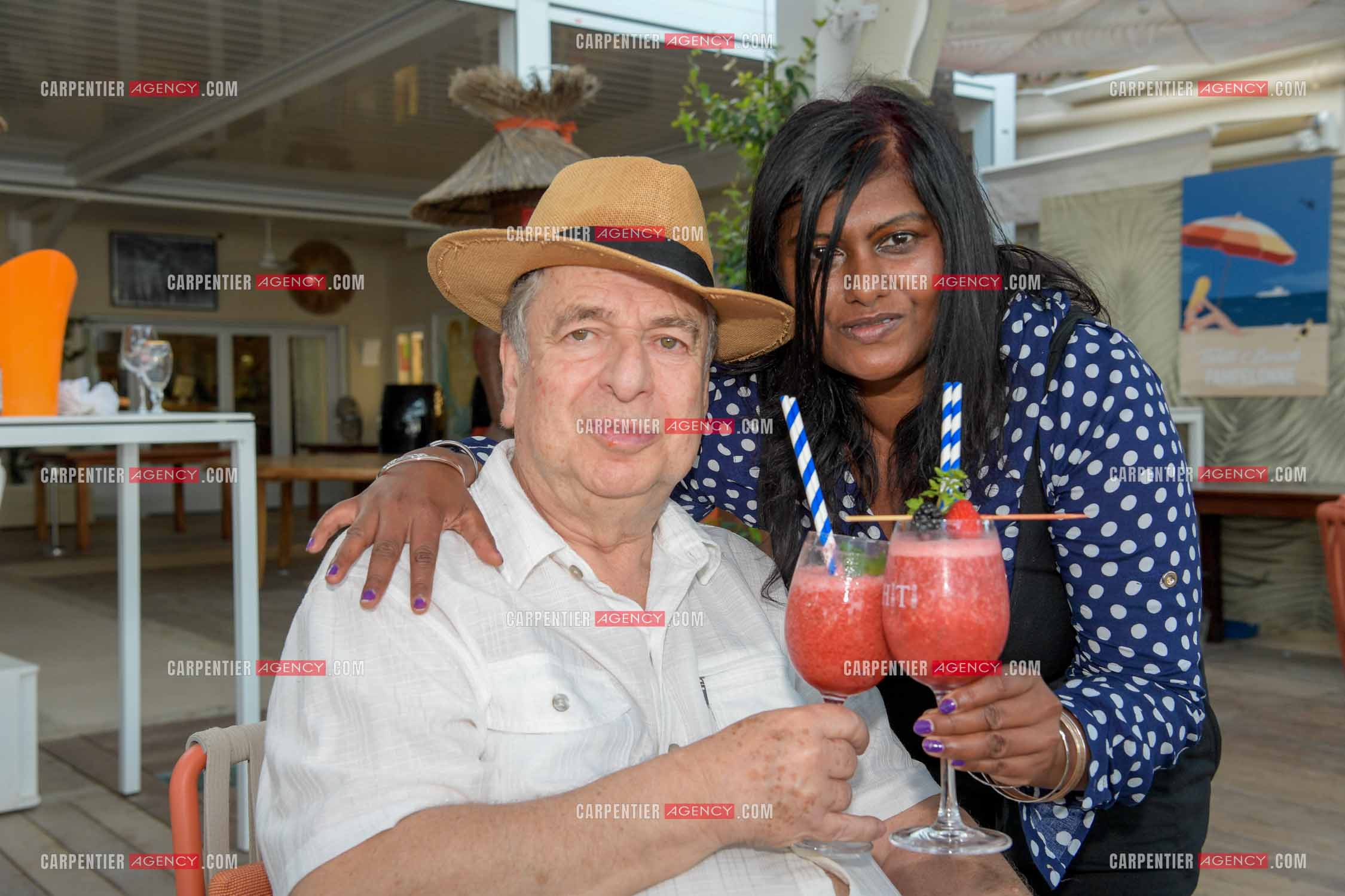 Paul-Loup Sulitzer lors d'une ballade sur le port de St Tropez. Ici en terrasse du bar de plage le " TAHAITI “  avec sa compagne  Supriya Answya Devi Rathoar.  ( Exclusif )