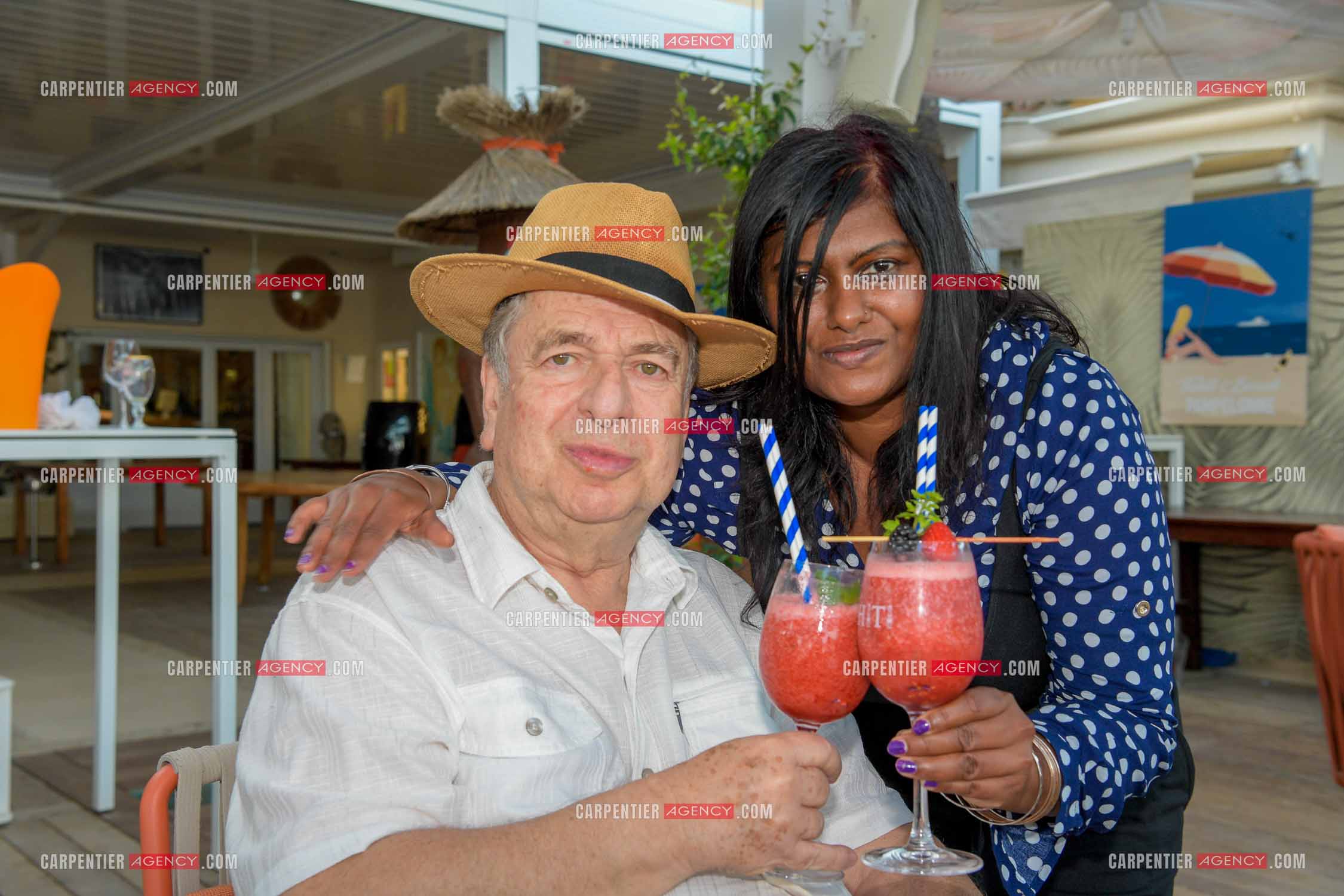 Paul-Loup Sulitzer lors d'une ballade sur le port de St Tropez. Ici en terrasse du bar de plage le " TAHAITI “  avec sa compagne  Supriya Answya Devi Rathoar.  ( Exclusif )