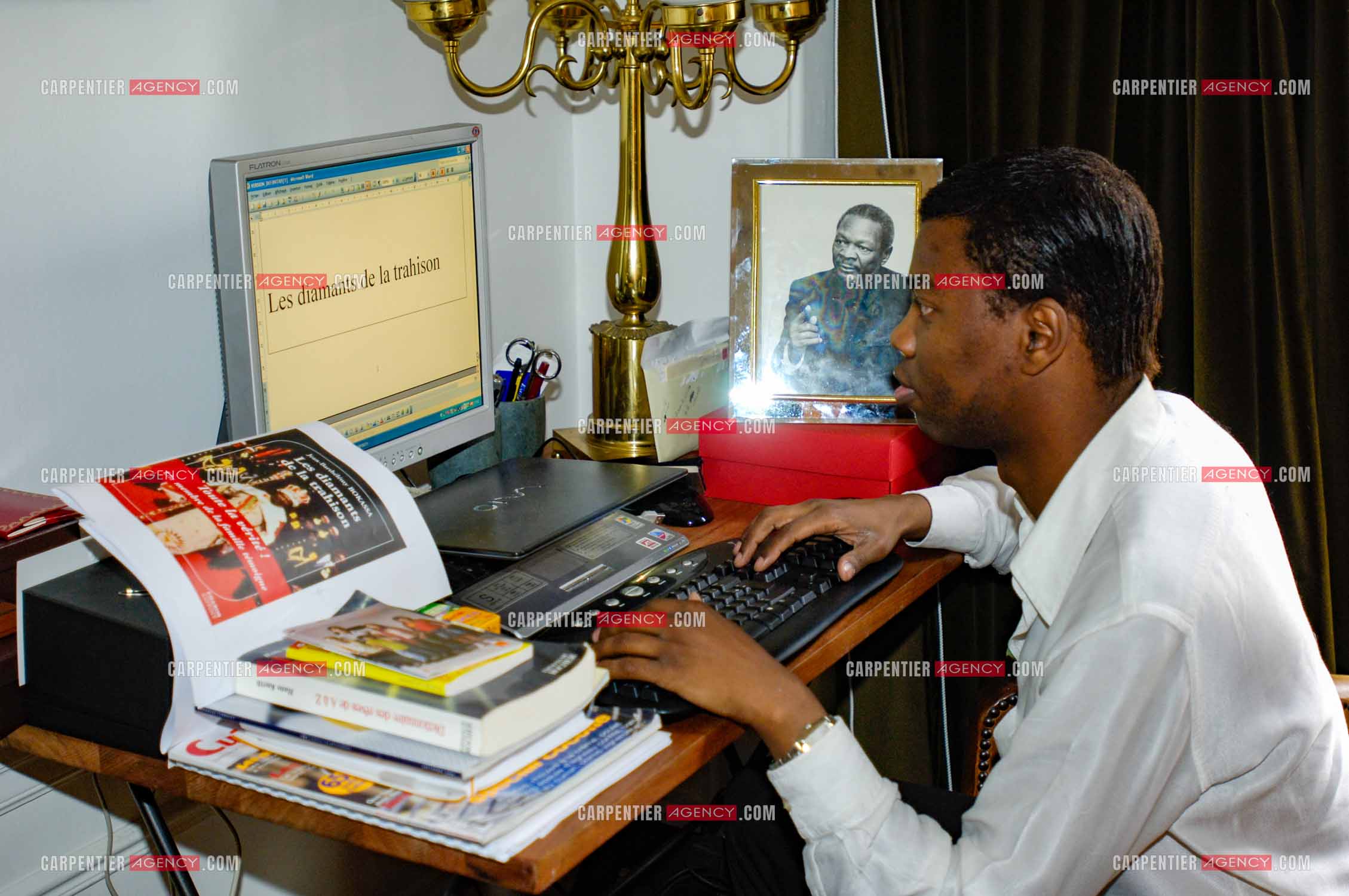 Jean-Barthélémy Bokassa, petit fils de l'empereur Bokassa Ier. Ici, dans son appartement parisien lors de l'écriture de son roman " Les Diamants de la Trahison “ aux côtés du portraits de son grand-père.  ( Exclusif )
